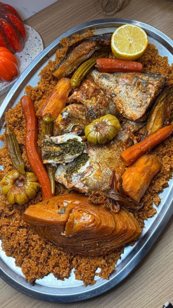 Thiébou dieune : riz rouge, poisson farci, carottes, manioc et légumes, servi dans un grand plat